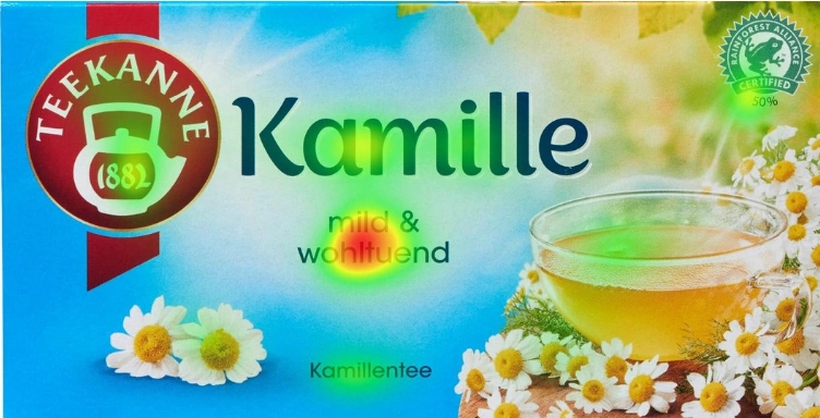 Eye-Tracking-Heatmap der Teekanne-Kamille-Verpackung. Die Fixationen konzentrieren sich auf Produkttitel, Logo, Produktbeschreibung und Zertifizierung – das groß platzierte Teeglas bleibt weitgehend unbeachtet.